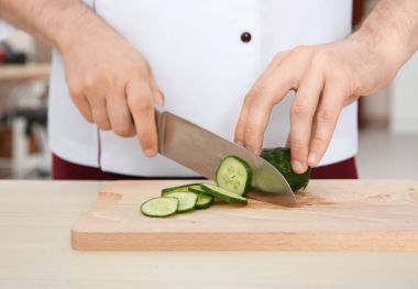 Chef slicing cucumbers on cutting board