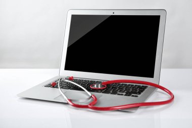 Laptop ve beyaz masada stetoskop