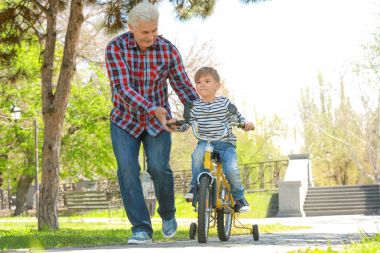 Sevimli küçük çocuk Bisiklet ve dedesi Bahar park at binme