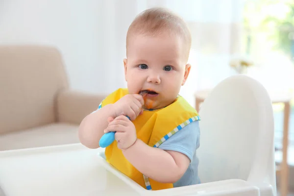 Симпатична дитина з ложкою сидить на кухні — стокове фото