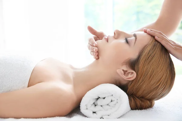 Jonge vrouw genieten van gezichtsmassage in spa salon — Stockfoto