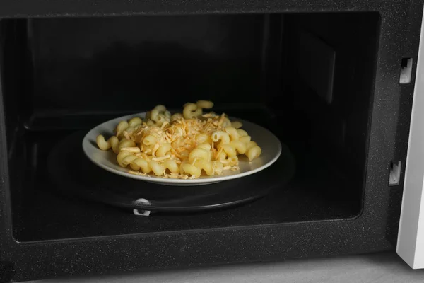 Plate with pasta in microwave — Stock Photo, Image