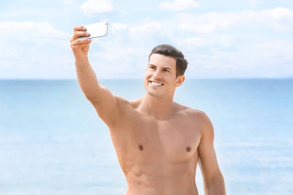 Schöner junger Mann macht Selfie am Strand — Stockfoto