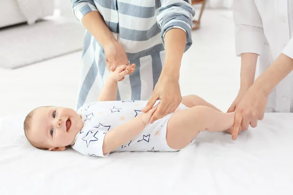 Ibu muda berdiri di dekat sofa sementara dokter memeriksa bayi di rumah — Stok Foto