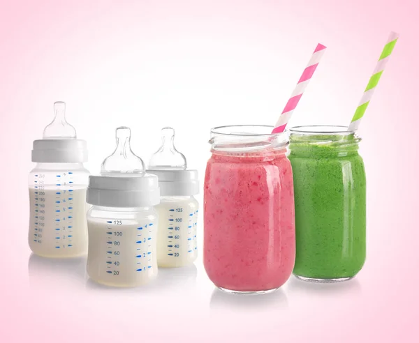 Feeding bottles with milk and jars of smoothies — Stock Photo, Image