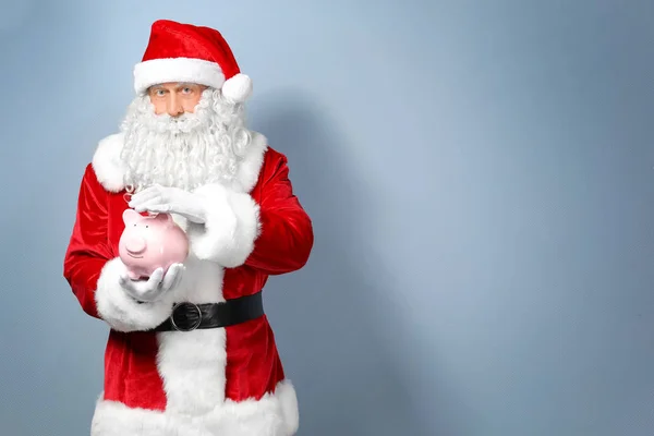 Santa Claus sosteniendo piggy bang sobre fondo claro — Foto de Stock