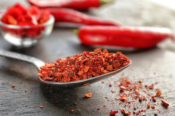 Red chili flakes in metal spoon — Stock Photo, Image