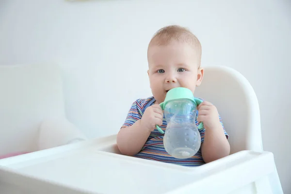 Cute baby drinking water from plastic bottle indoors — Stock Photo, Image