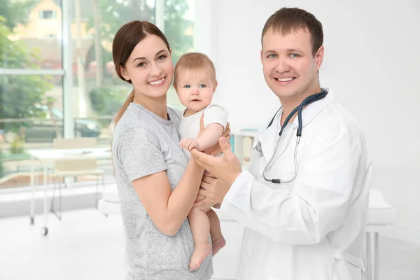 Smiling doctor and woman with baby indoors — Stock Photo, Image