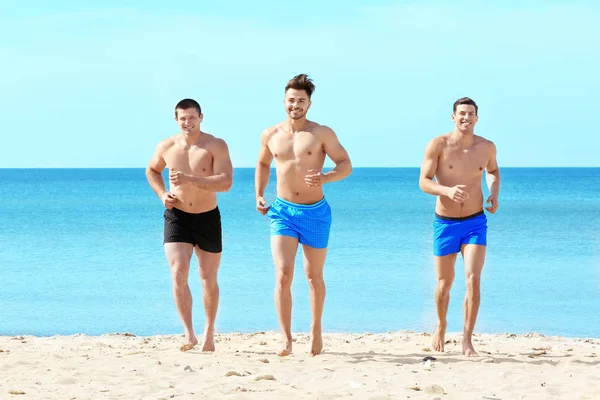Gutaussehende junge Männer laufen am Strand des Meeres — Stockfoto