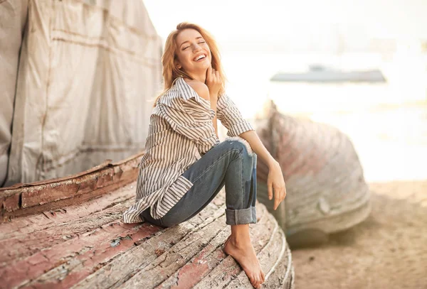 Woman sitting on old overturned boat — Stock Photo, Image