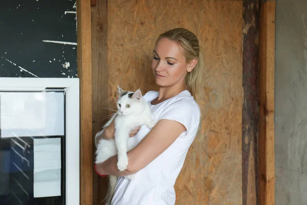 Female volunteer holding white homeless cat in animal shelter