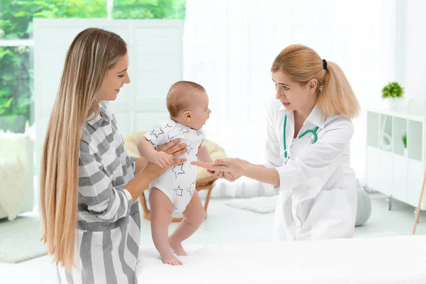 Junge Mutter hält ihr süßes Baby, während der Arzt arbeitet — Stockfoto