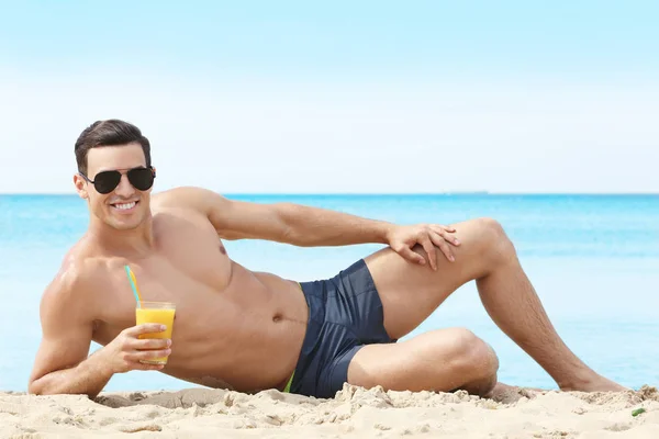 Bello giovanotto con drink sulla spiaggia di mare — Foto Stock