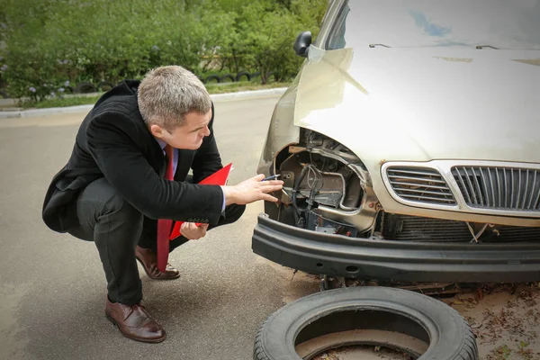 Biztosítási férfi ellenőrzési törött autó — Stock Fotó