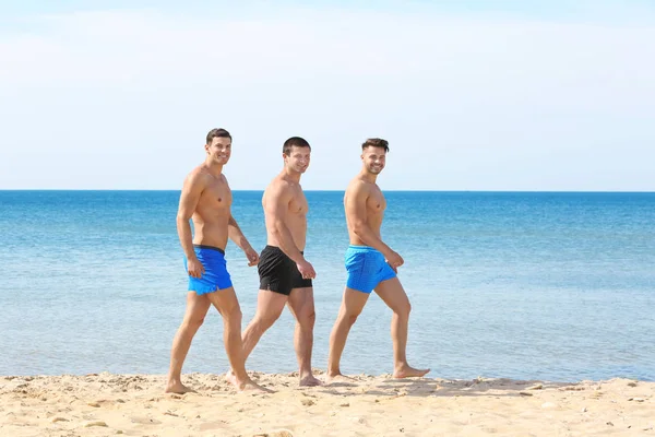 Hübsche junge Männer, die am Meeresstrand spazieren gehen — Stockfoto