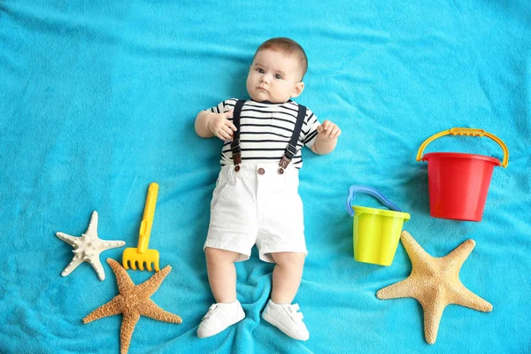 Şirin bebek üzerinde mavi yatak örtüsü yalan deniz yıldızı ve plaj oyuncakları ile. Tatil kavramı