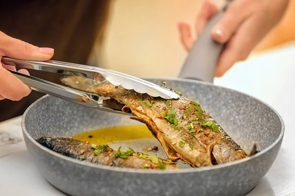 Şef tava üzerinde lezzetli balıklar hazırlanıyor