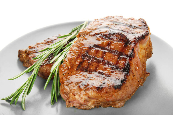 Plate with tasty steaks on white background