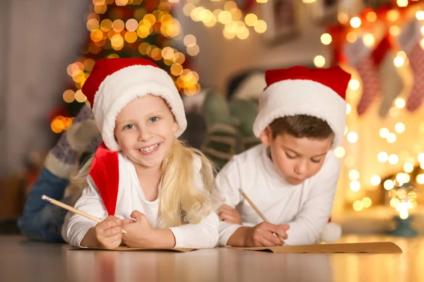 Bonito crianças escrevendo carta para Papai Noel no quarto decorado para o Natal — Fotografia de Stock