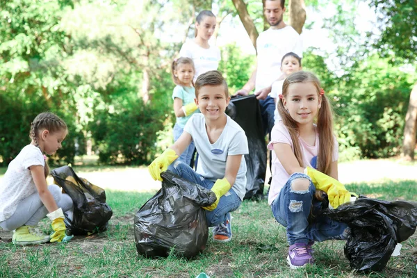 Jovens voluntários e crianças coletando lixo no parque — Fotografia de Stock
