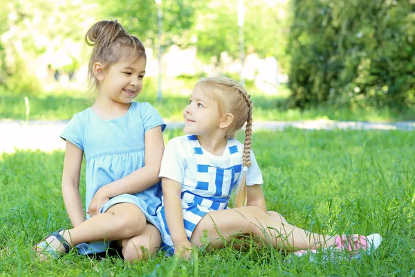 Niedliche kleine Mädchen sitzen auf grünem Gras im Park — Stockfoto