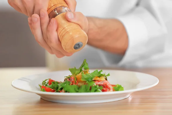 Přidávání koření do salátu mužské kuchař — Stock fotografie
