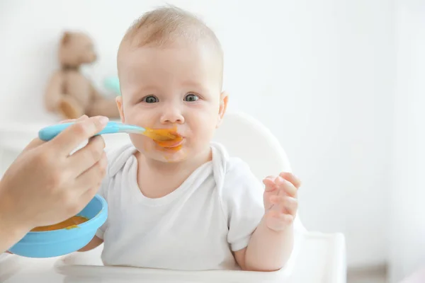 Mãe alimentando bebê com colher dentro de casa — Fotografia de Stock