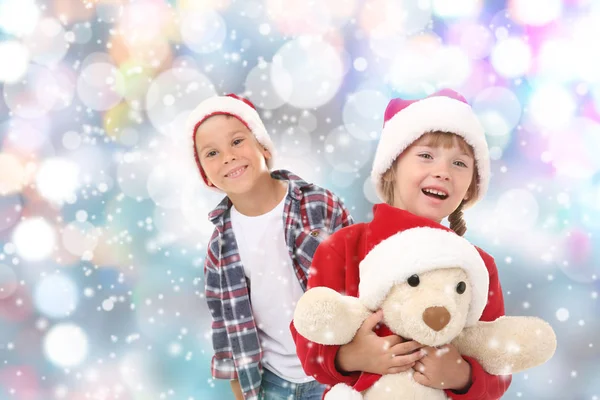 Милые маленькие дети в шляпах Санта-Клауса на фоне размытых огней — стоковое фото
