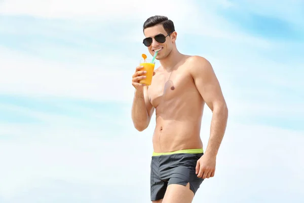 Schöner junger Mann mit Drink am Strand — Stockfoto