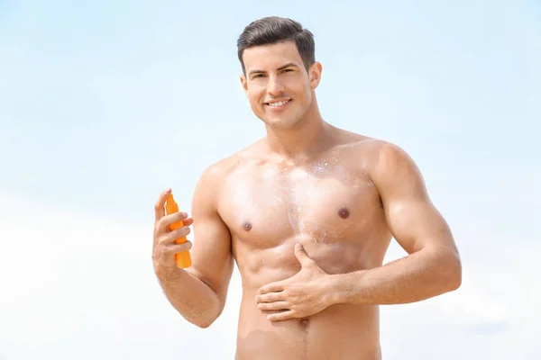 Bonito jovem aplicando protetor solar creme na praia do mar — Fotografia de Stock