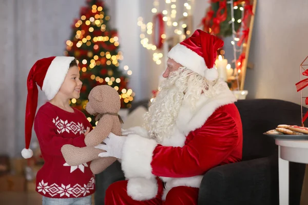 Oda güzel Noel süslemeleri ile sevimli çocuk oyuncak ayı veren Santa