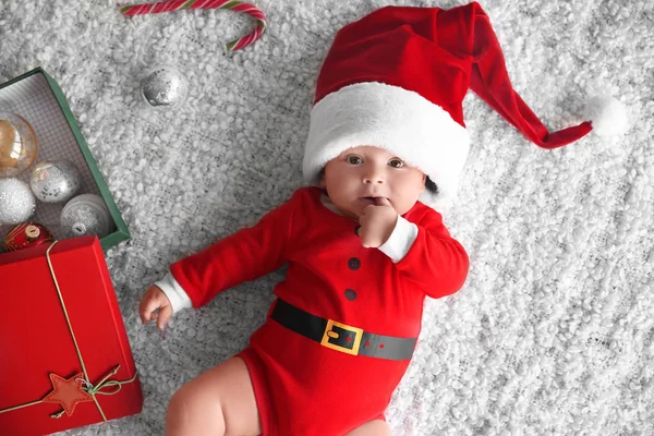 Niedliches kleines Baby im Weihnachtsmannkostüm auf weichem Stoff — Stockfoto