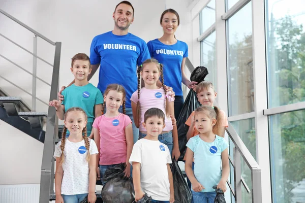 Heureux bénévoles et enfants avec des sacs poubelle debout sur les escaliers — Photo