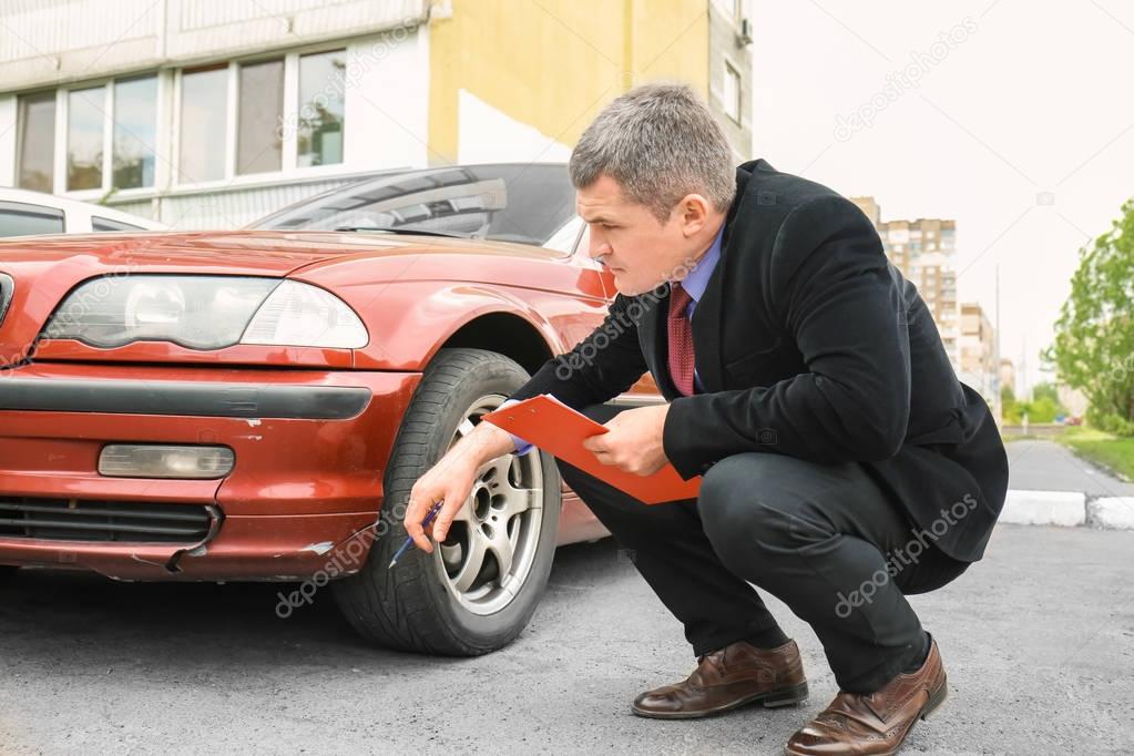 Insurance man checking broken car 