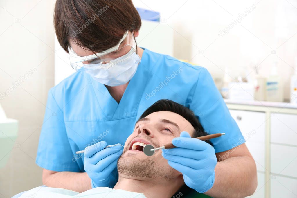 Dentist examining man's teeth in clinic
