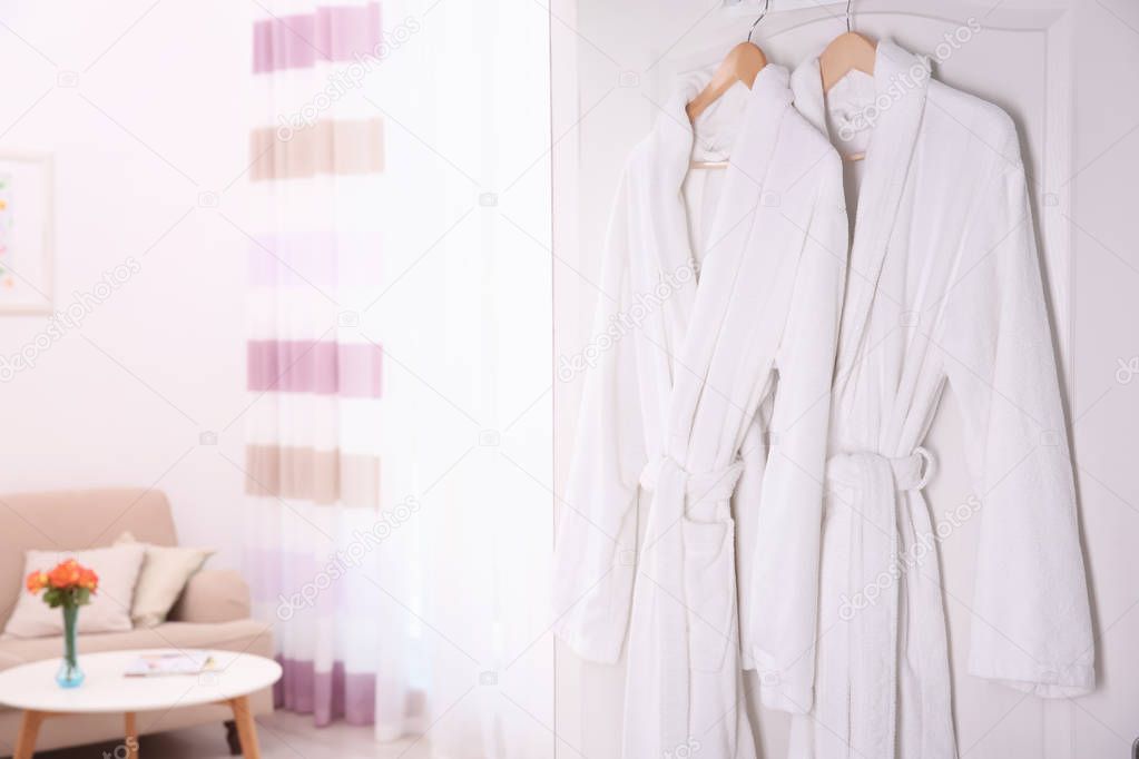 Bathrobes hanging on white door in room