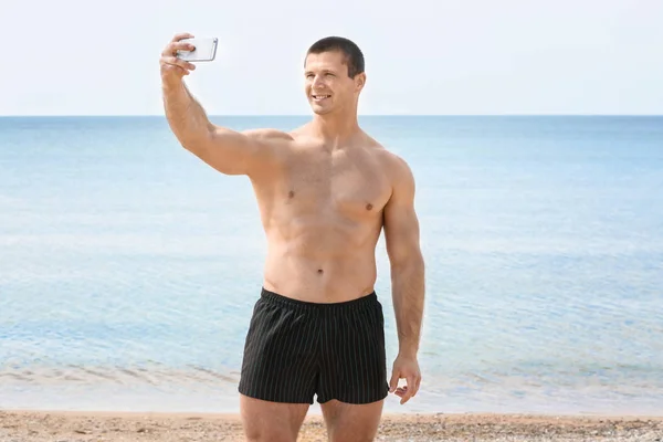 Bello giovane uomo prendendo selfie sulla spiaggia di mare — Foto Stock