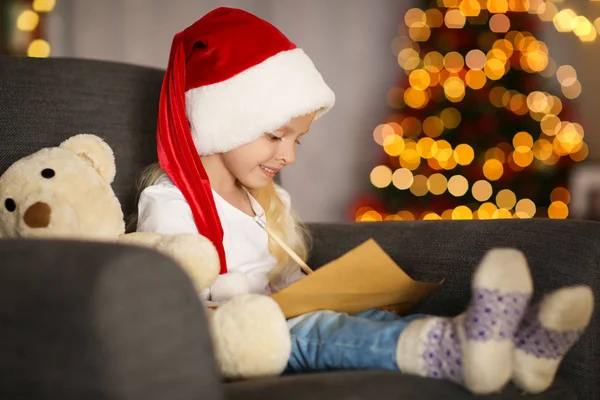 Sevimli kız evde Noel Baba'ya mektup yazma Noel şapkalı