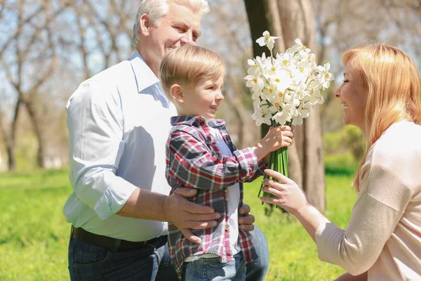 Milý Chlapeček Dědečkem Dává Kytice Babičce Jaře Parku Slunečný Den — Stock fotografie