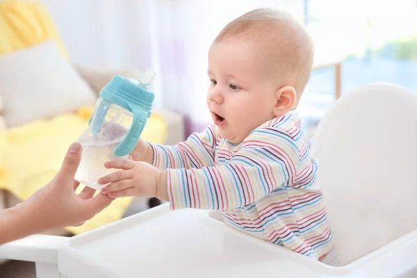 Mor ger nappflaska med vatten inomhus — Stockfoto