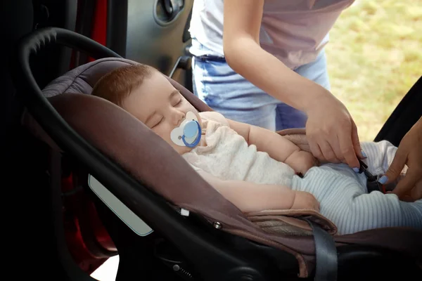 Мати кріпиться спати дитини до дитячого сидіння безпеки всередині автомобіля — стокове фото