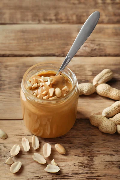 Tarro y cuchara con mantequilla de maní cremosa — Foto de Stock