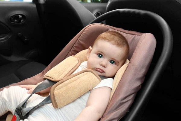 Очаровательный ребенок отдыхает на детском сиденье внутри автомобиля
