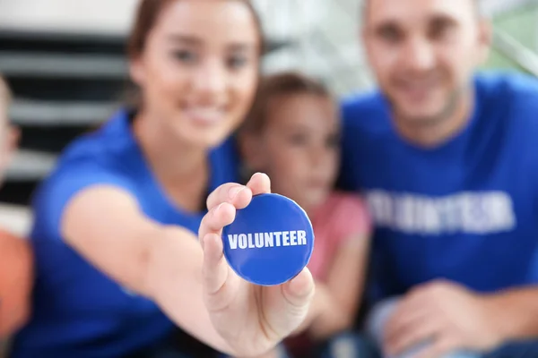Volunteer button in young woman's hand indoors — Stock Photo, Image