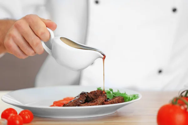 Chef pouring sauce on meat — Stock Photo, Image
