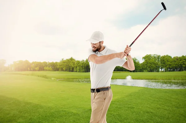 Молодой человек играет в гольф на поле — стоковое фото