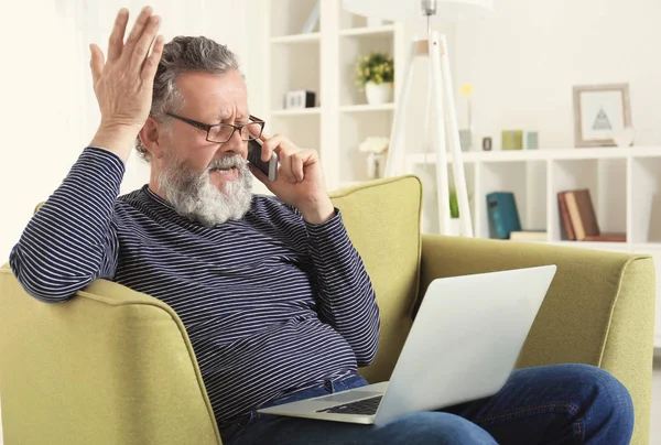 Vacker äldre man sitter i fåtölj med laptop — Stockfoto