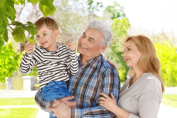 Niedliche glückliche Junge mit Großeltern im Frühlingspark an einem sonnigen Tag — Stockfoto