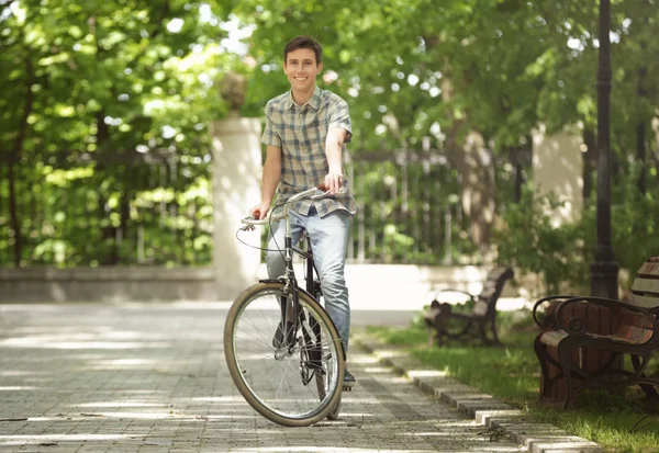 Junger schöner Mann mit Fahrrad an sonnigem Tag im Freien — Stockfoto